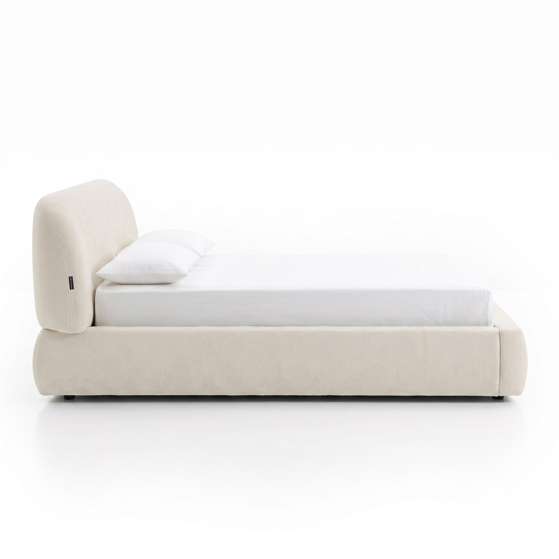 Side view of an off-white upholstered bed on a white background