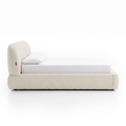 Side view of an off-white upholstered bed on a white background