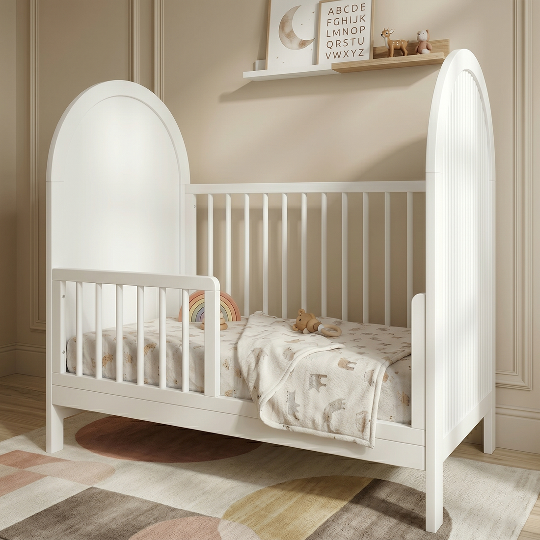 White wooden crib in a warmly lit nursery with a patterned blanket, toys, and shelf decor above