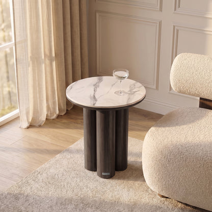 Round side table styled in a living room next to an armchair
