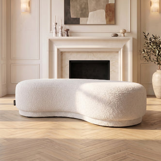 Curved cream white upholstered bench seat in a stylish living room
