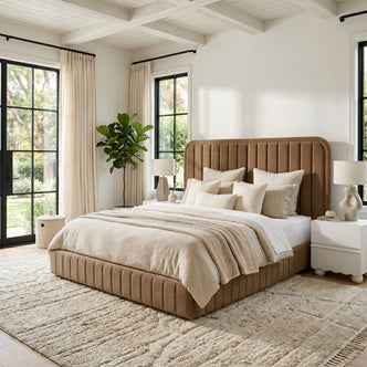 Lifestyle shot of upholstered bed in bright bedroom with windows, nightstands and plant