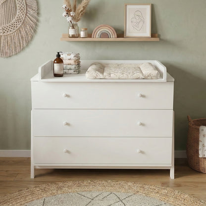 White three-drawer dresser with changing tray styled in boho nursery