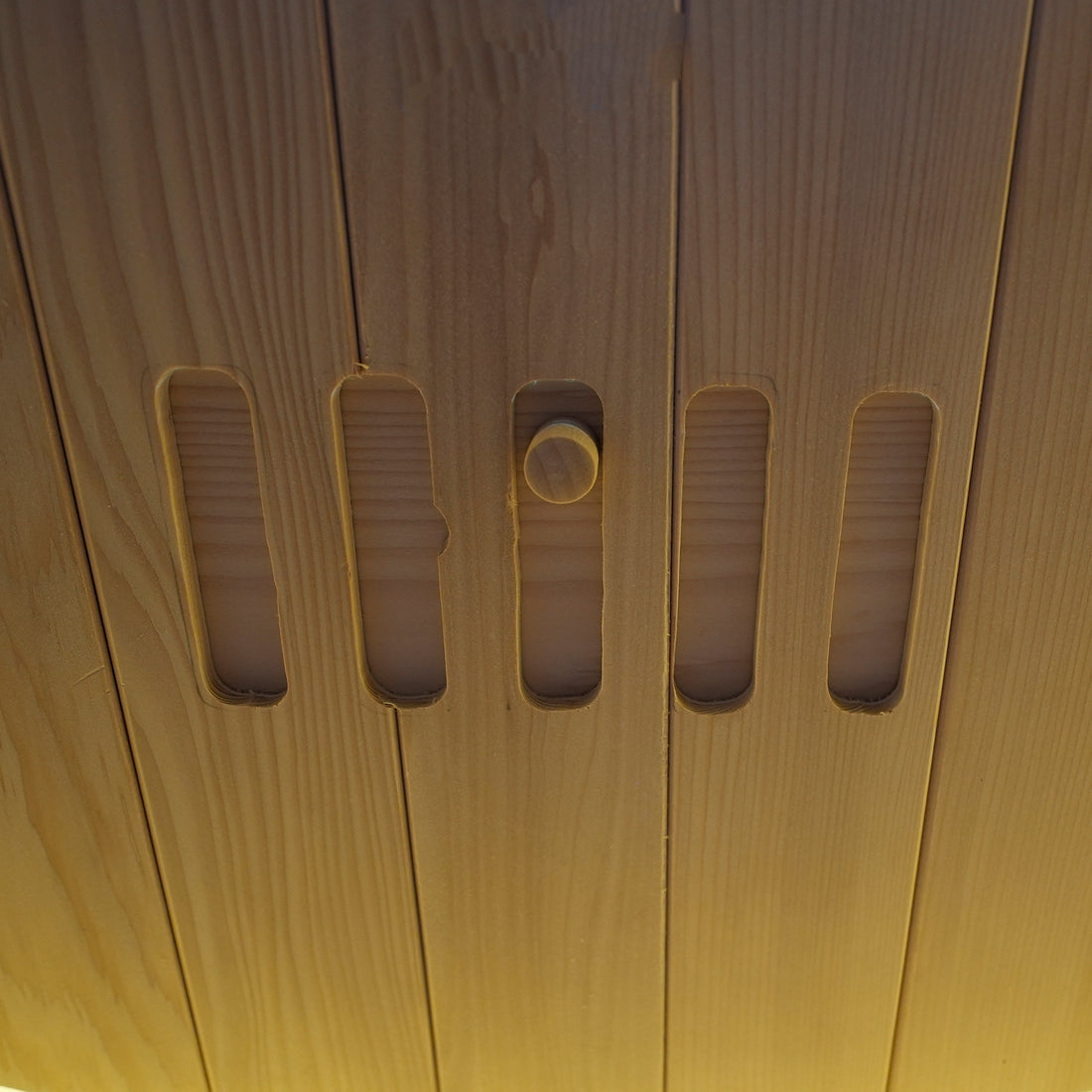 Close-up detail of a wooden surface with vertical slots and a knob