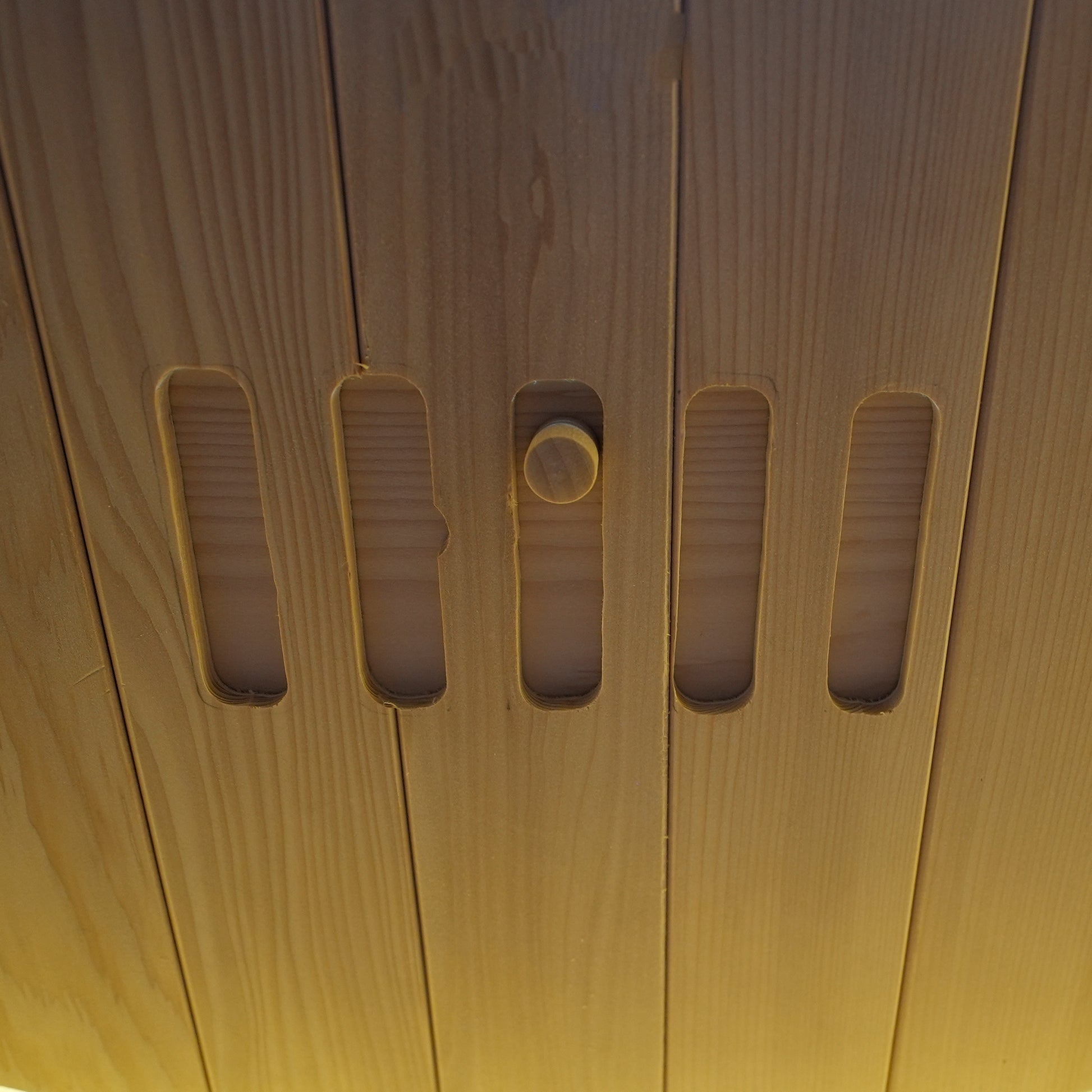 Close-up detail of a wooden surface with vertical slots and a knob