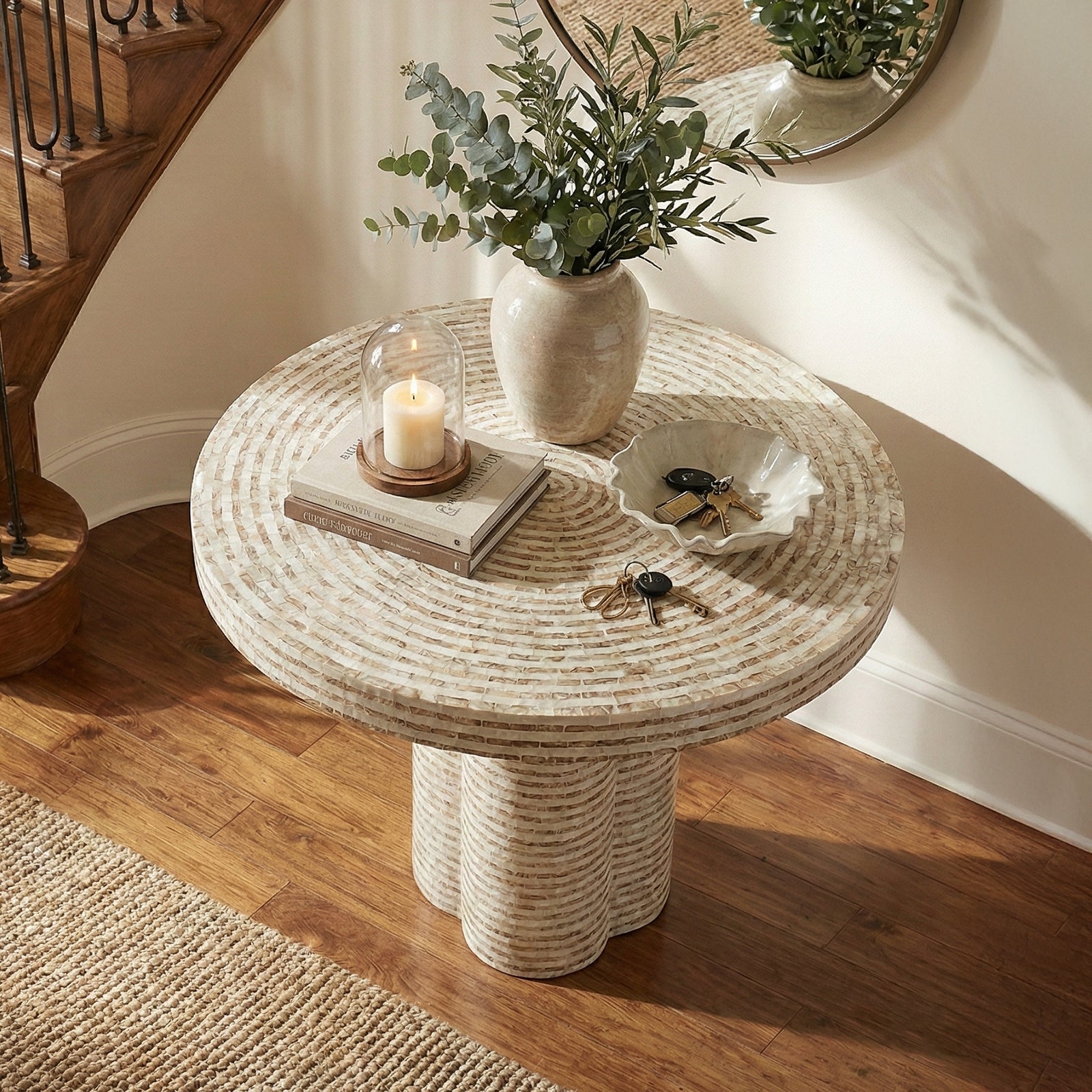 Round textured side table with vase, candle, and book in cozy interior