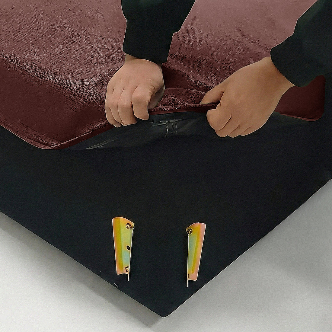 Hands lifting cover corner of mattress or furniture base to reveal inner structure