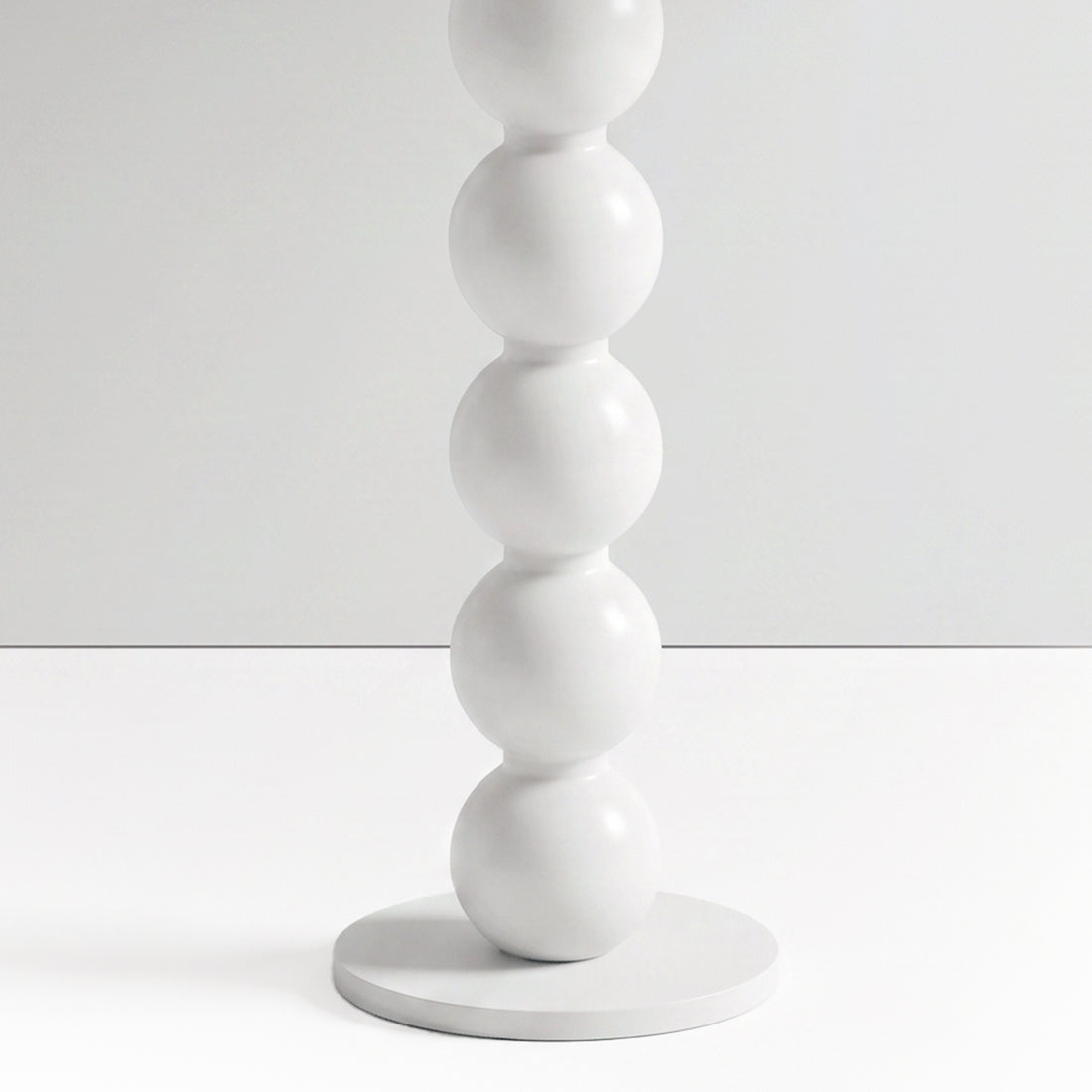 Close-up partial view of stacked white spheres on a furniture base against a white background