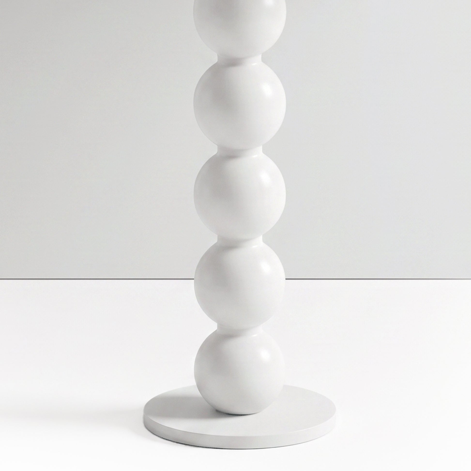 Close-up partial view of stacked white spheres on a furniture base against a white background