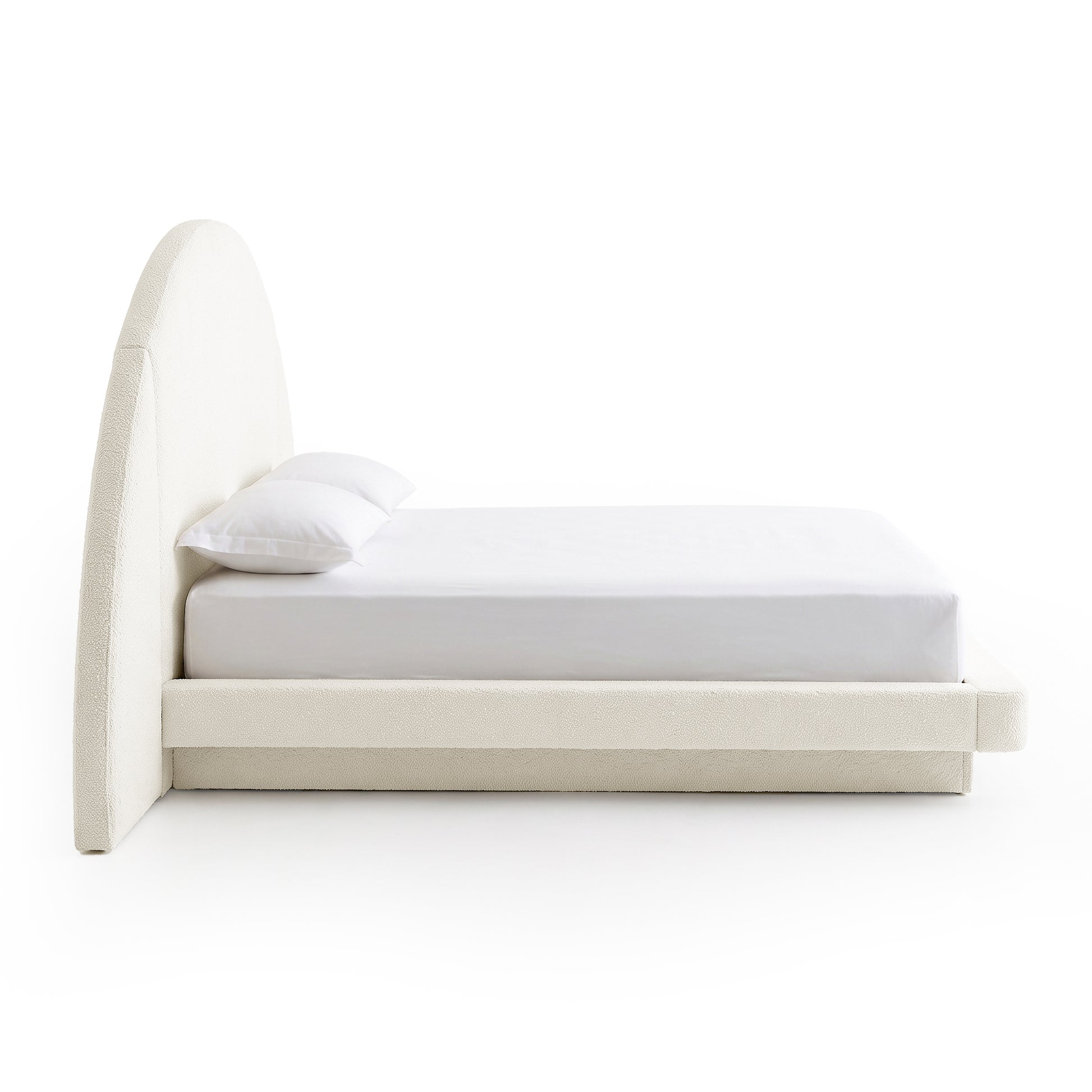 Side view of a modern upholstered bed with arched headboard on a white background