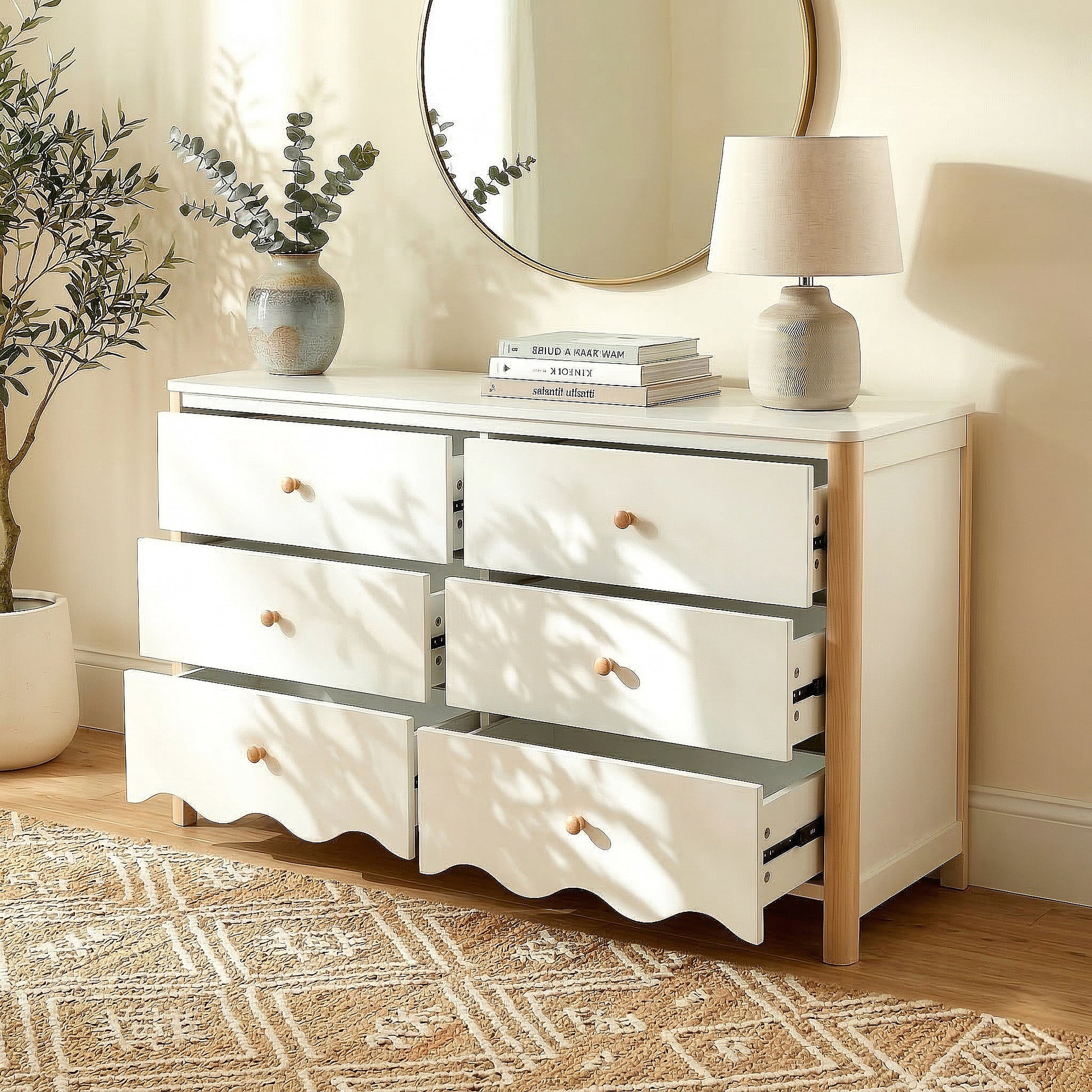 White and wood six-drawer dresser in a bright room with vase, lamp, mirror, plant, and open drawers