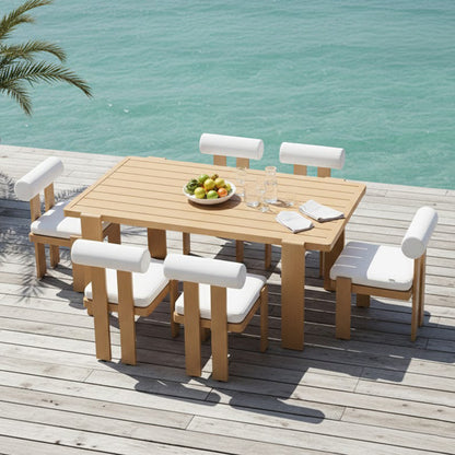 Positano 6 Seater Aluminium Outdoor Dining Set in White on a wooden deck with fruit bowl, glass carafes, and white-cushioned chairs, overlooking turquoise water beneath palm fronds.