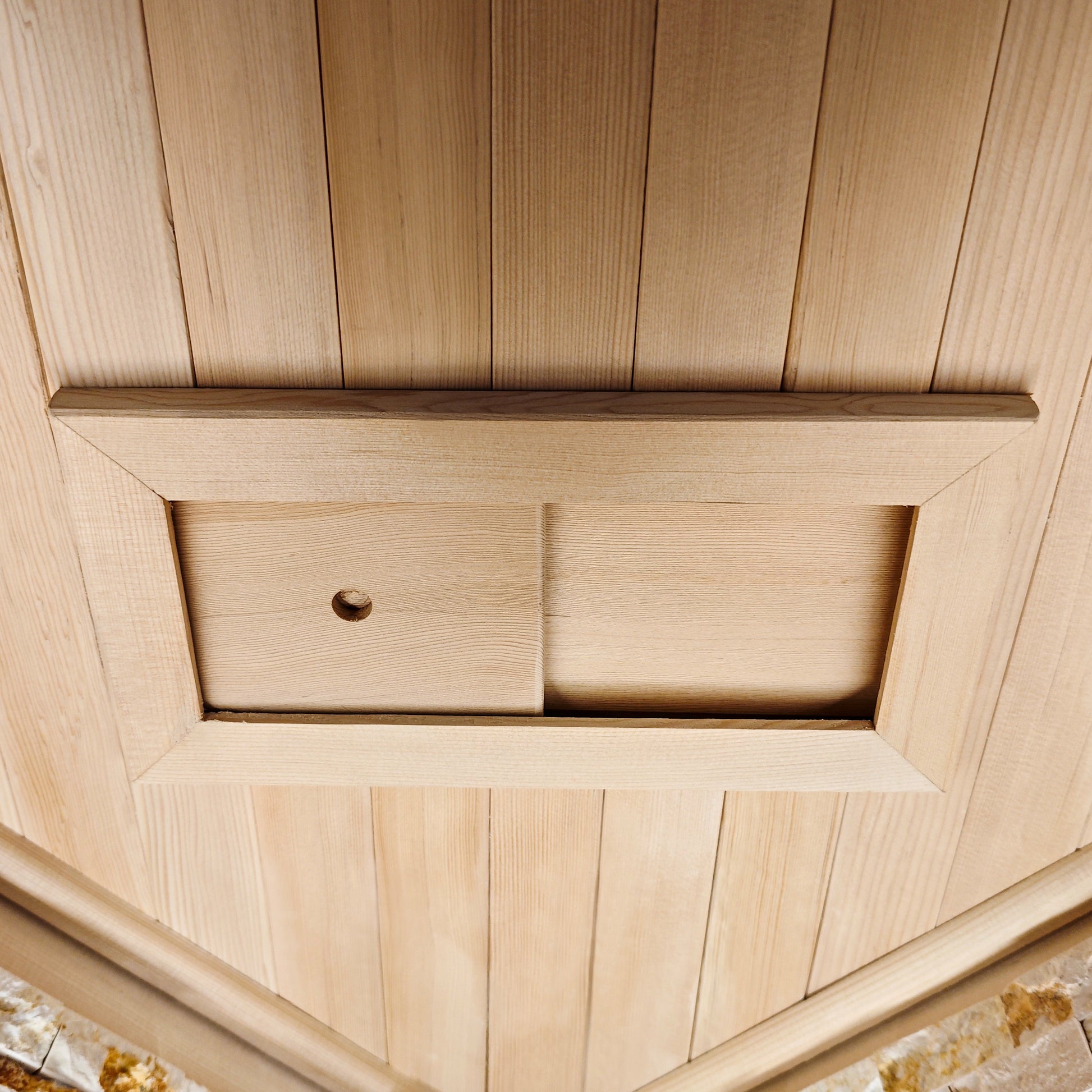 Rectangular wooden hatch or access panel set into a wood-paneled surface.