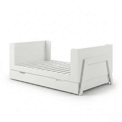 White toddler bed frame on white background angled view showing trundle drawer