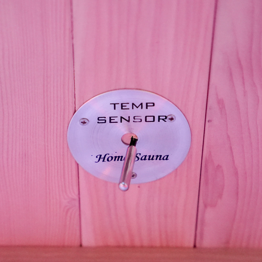 Close-up of a temperature sensor mounted on a wooden sauna wall