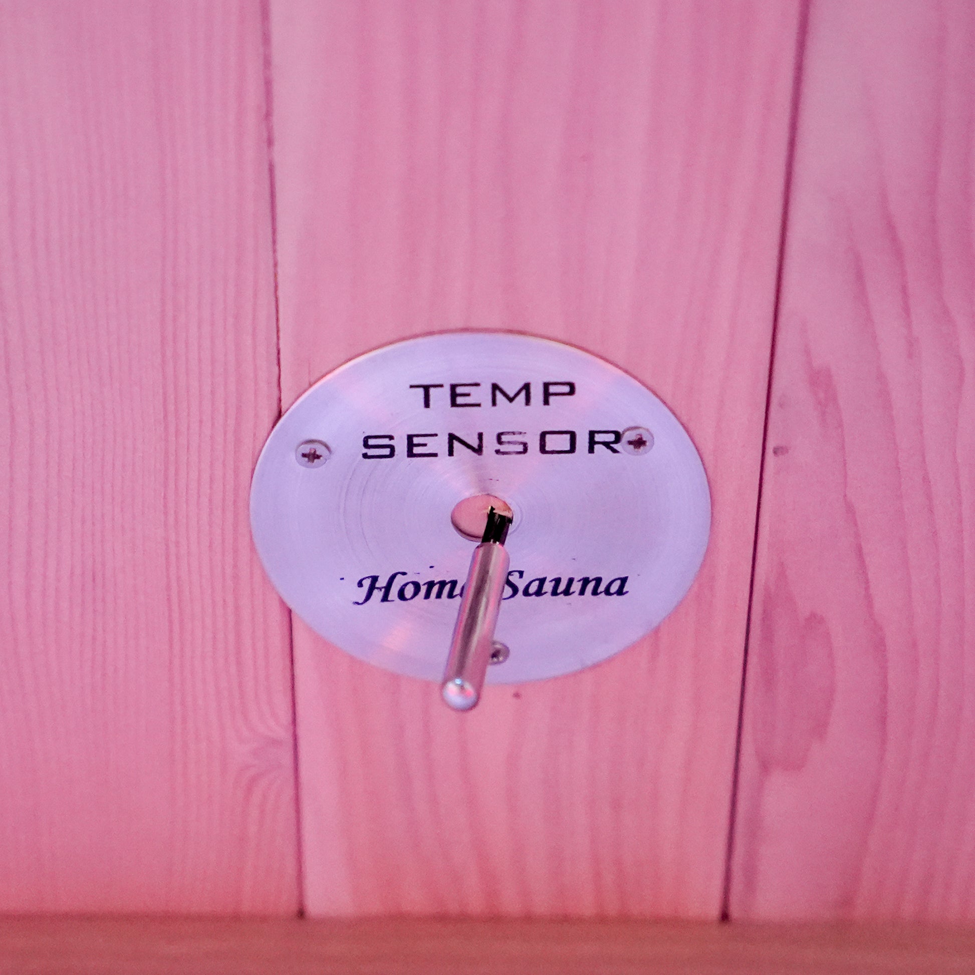 Close-up of a temperature sensor mounted on a wooden sauna wall