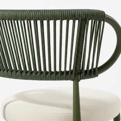 Cabria 9 Piece Sintered Stone Outdoor Dining Set in Green features a modern chair with an olive green, powder-coated metal frame and a backrest of vertical rope strands, paired with an off-white cushion.