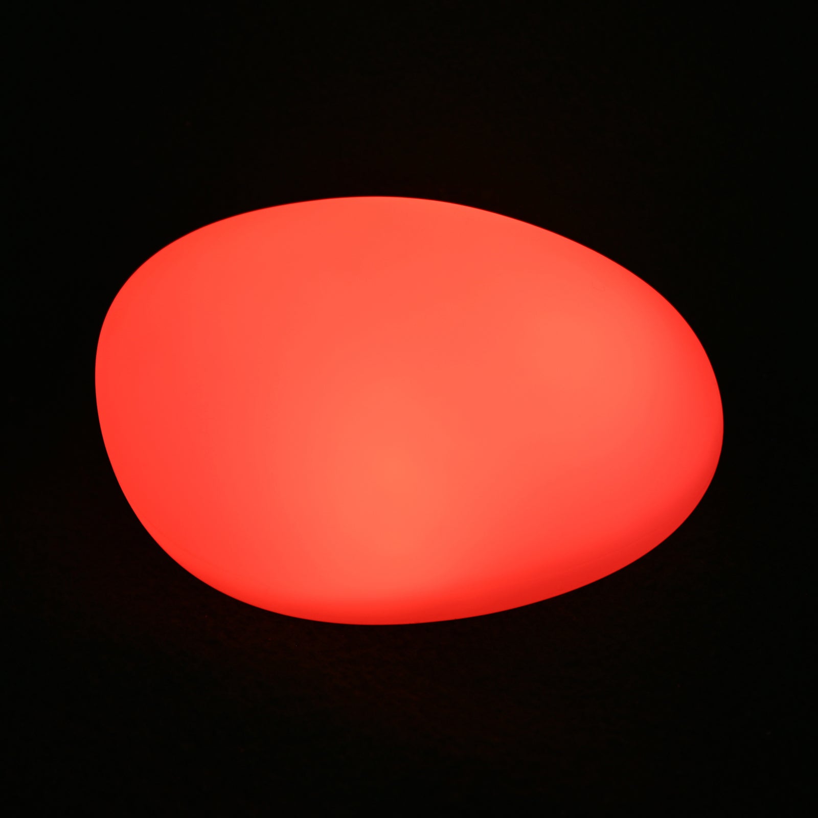 Solar Outdoor LED Rock Light Waterproof Garden Lamp glows red, resembling a smooth pebble, set against a black background, showcasing its decorative, cordless design for ambient garden lighting.