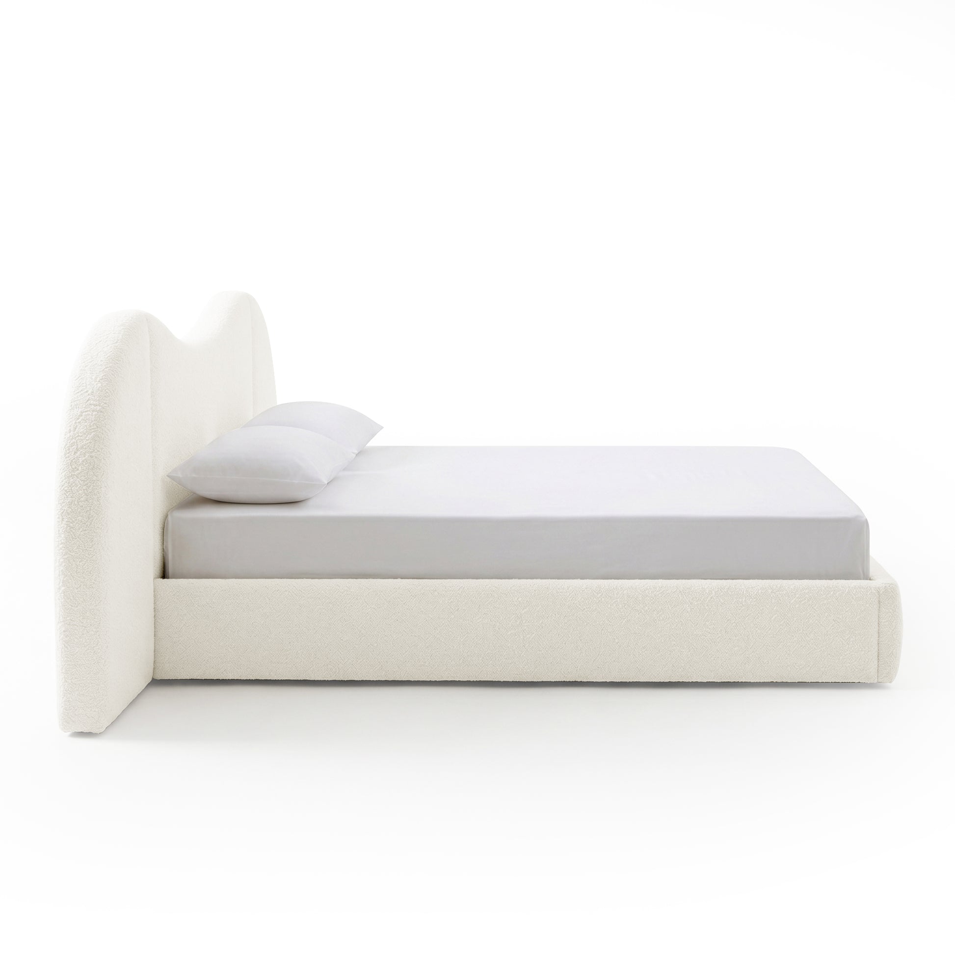White upholstered bed with wavy headboard on white background