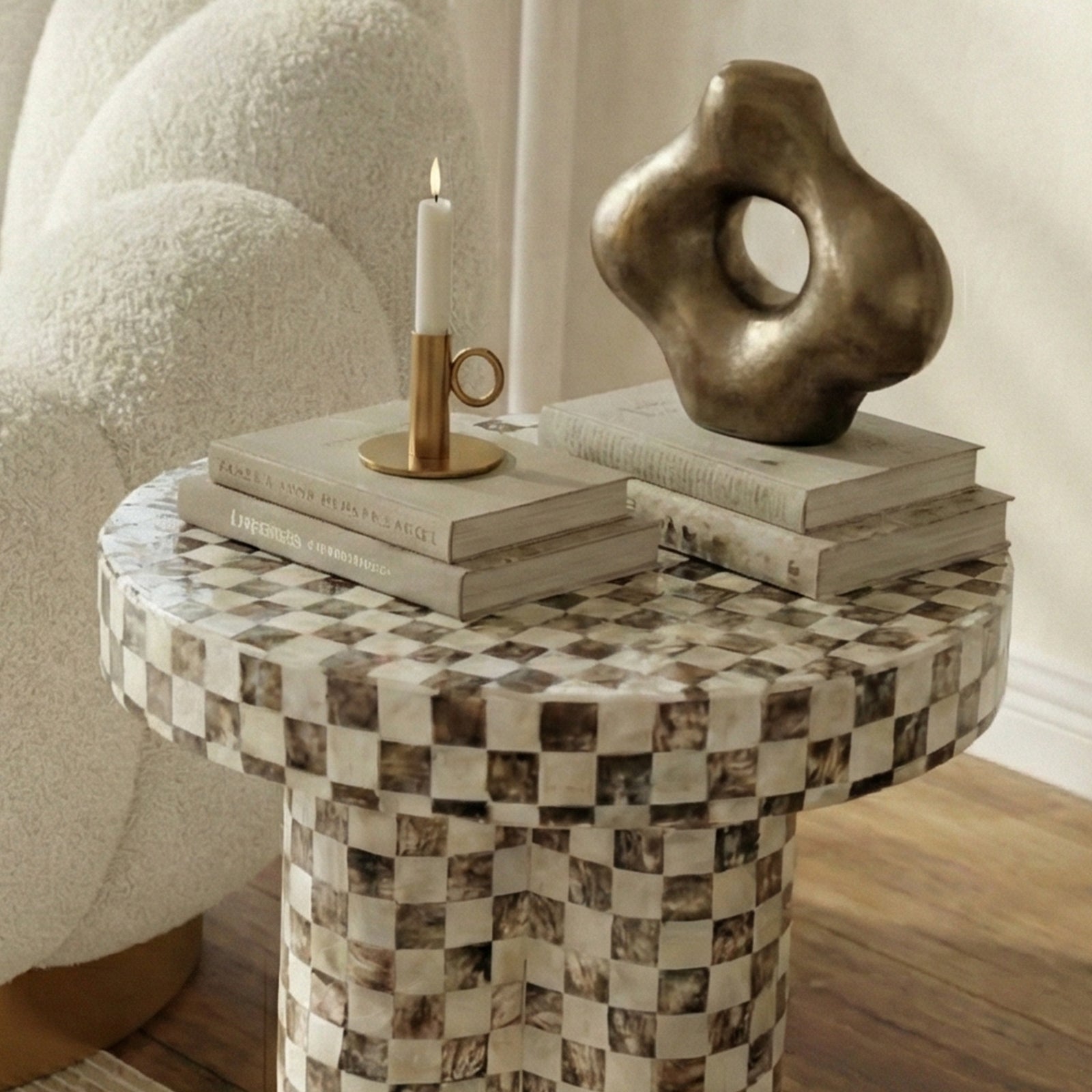 Partial view of checkered side table with books and candle in a cozy room