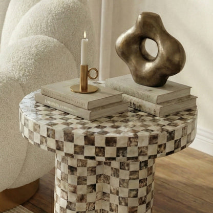 Partial view of checkered side table with books and candle in a cozy room