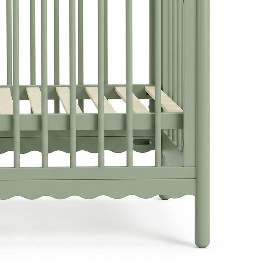 Close-up of crib's slatted base and scalloped edge