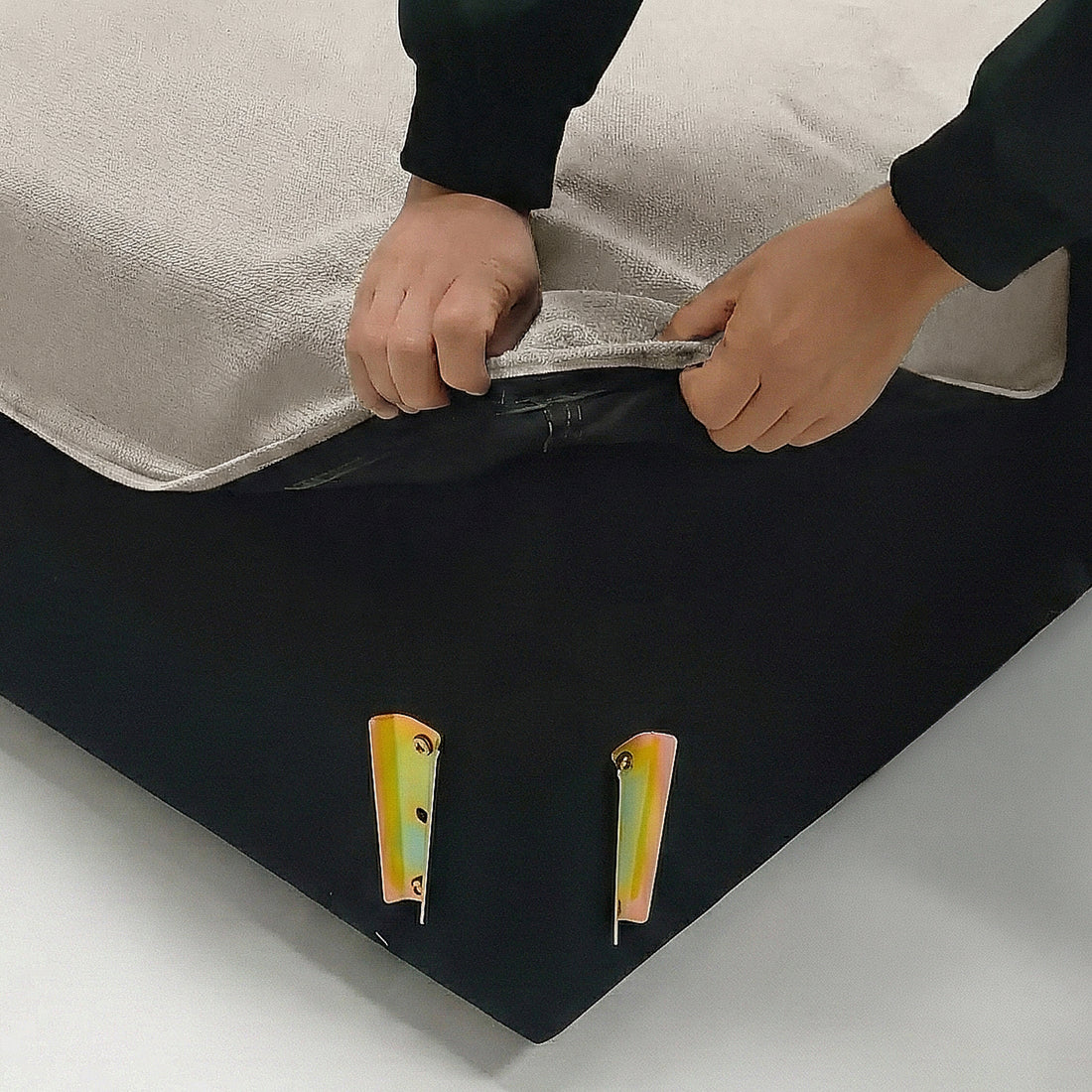 Hands unzipping beige fabric cover on furniture in a lifestyle setting