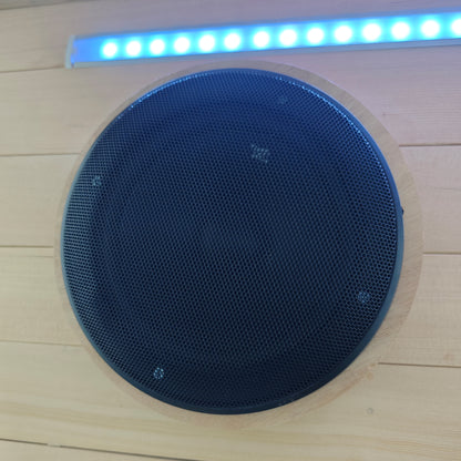 Black circular speaker installed in a wood-paneled surface with blue LED light above