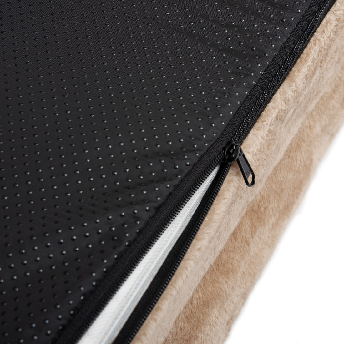 Close-up of beige cushion with black anti-slip underside and partially opened zipper