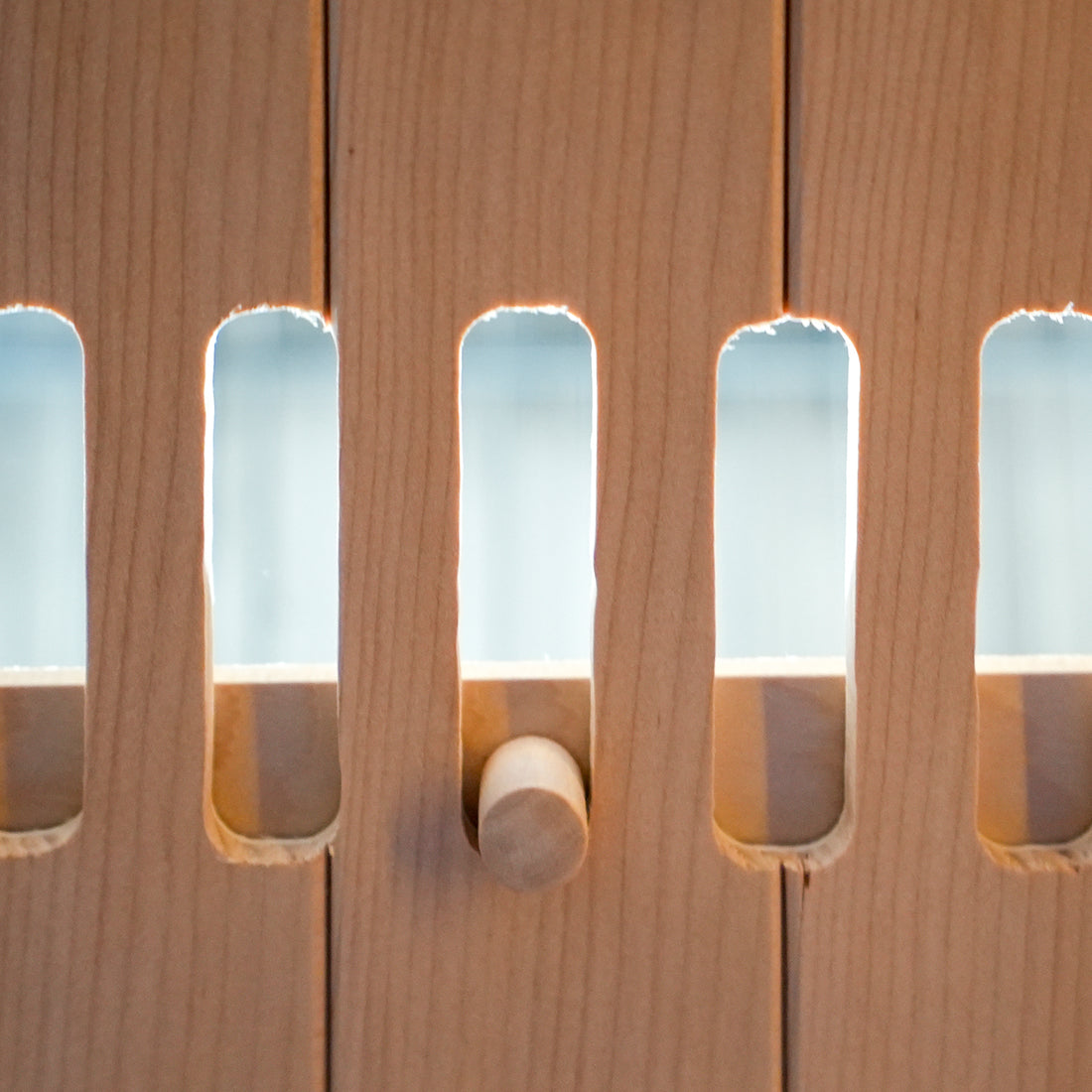 Close-up of light wood slatted panel with a wooden peg