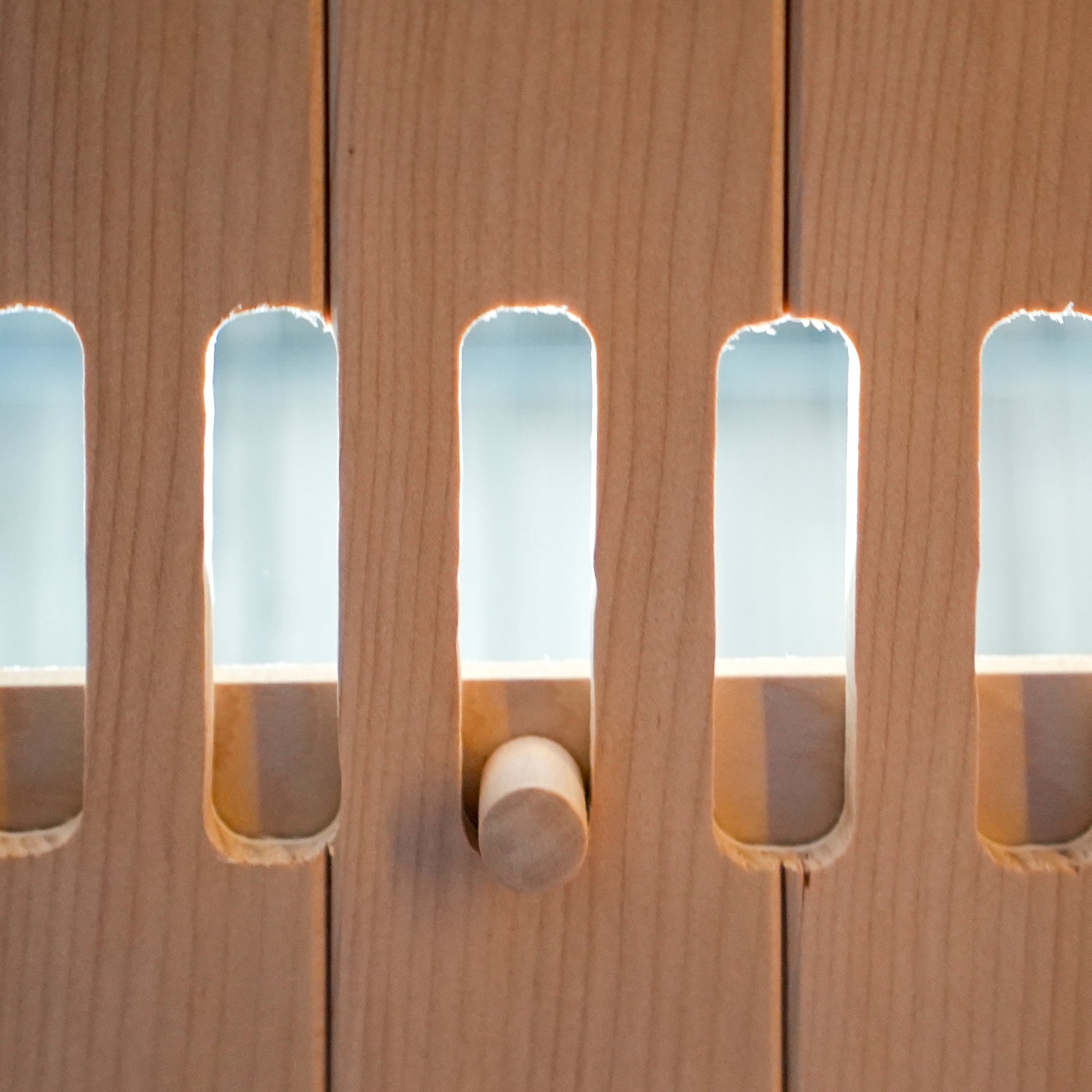 Close-up of light wood slatted panel with a wooden peg