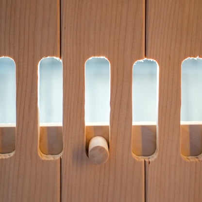 Close-up of light wood slatted panel with a wooden peg