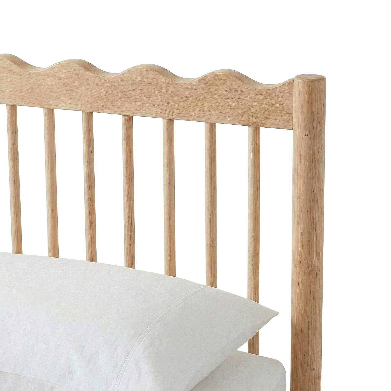Close-up of bed frame headboard with scalloped edge and two pillows on white background