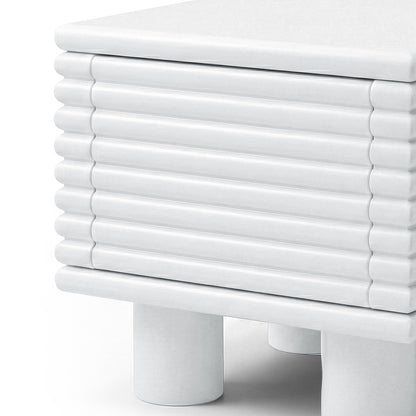 Partial view of a white ribbed side table on white background