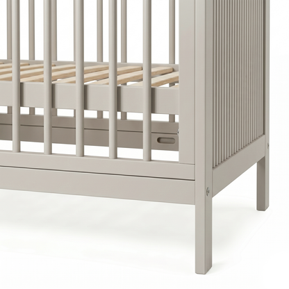 Close-up of lower corner and slats of crib on white background