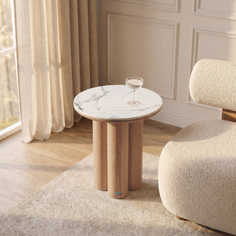 Modern round side table styled in a bright room with chair and curtains