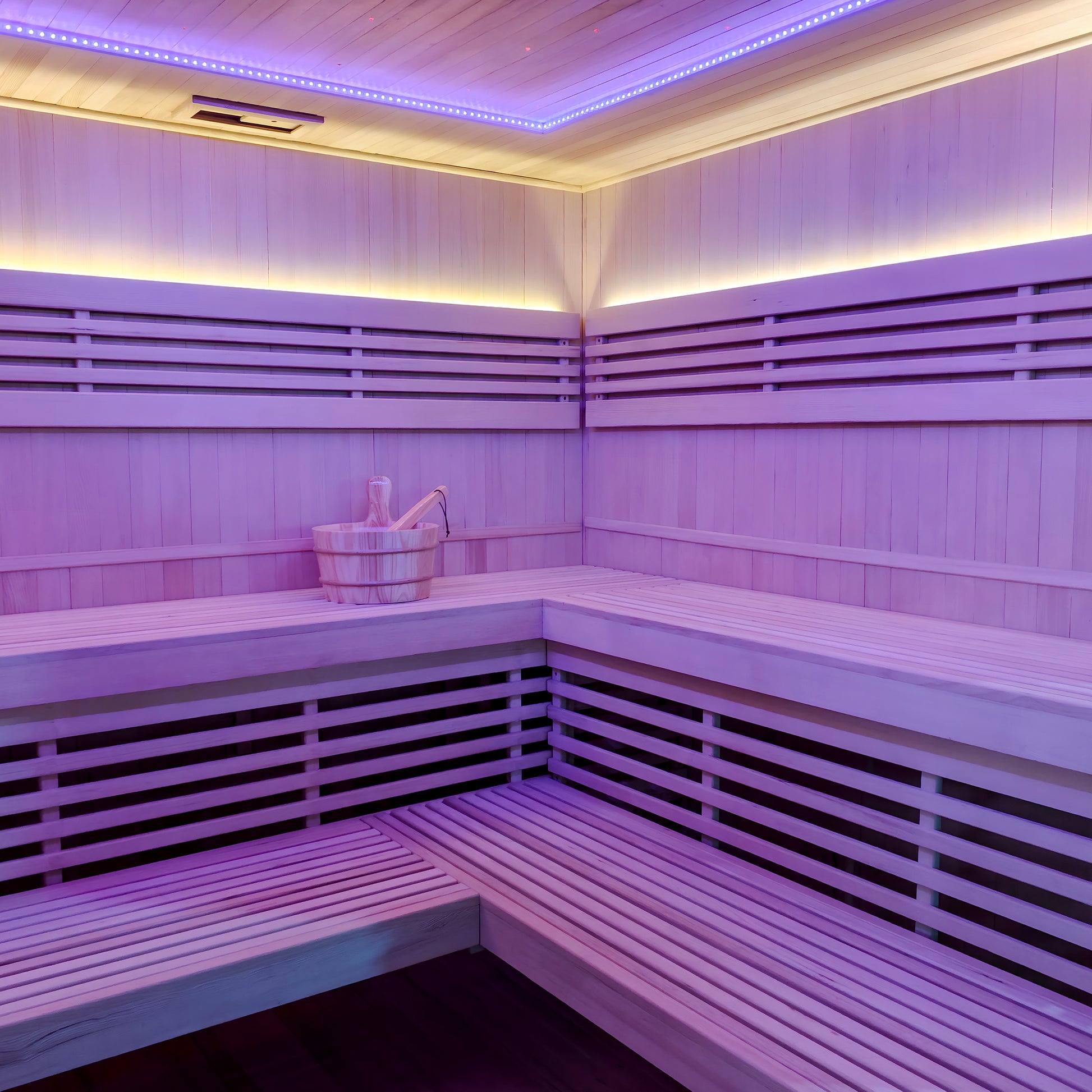 Modern wooden sauna interior with purple and yellow LED lighting and bench seating
