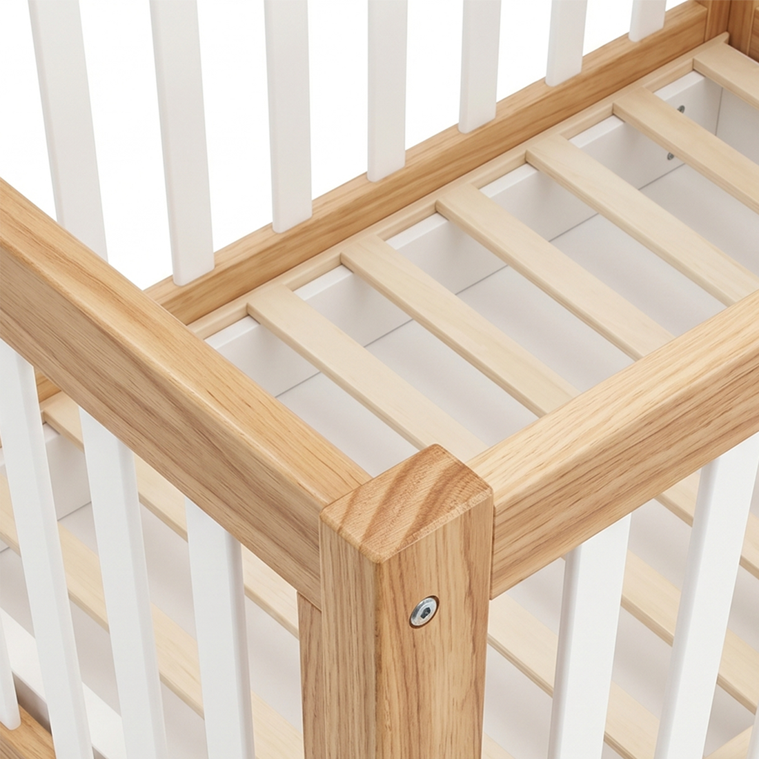 Close-up of a crib corner with wood frame and white slats