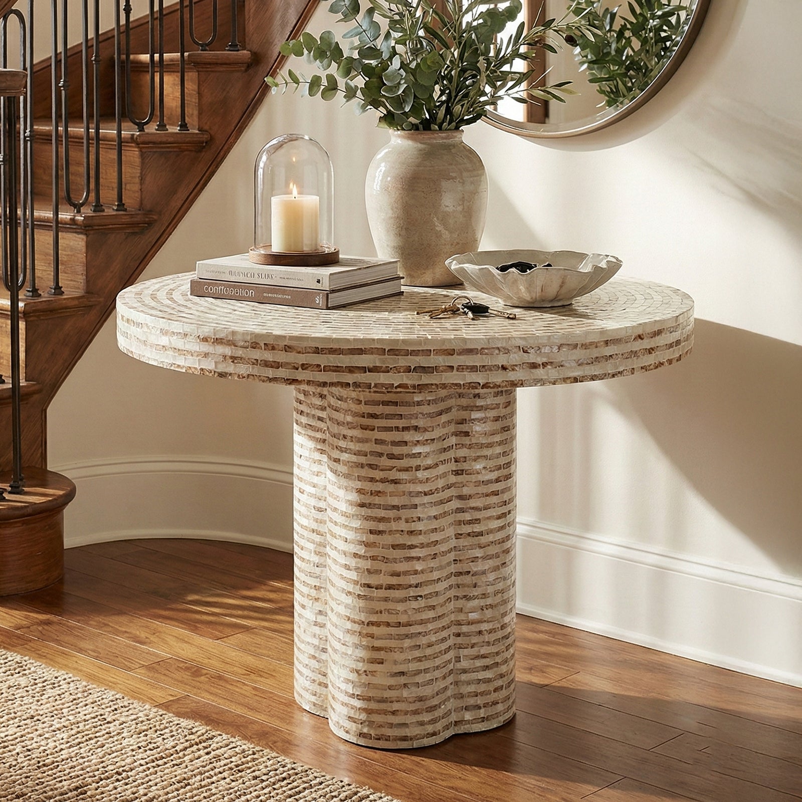 Round accent table next to staircase with mirror and decorative items