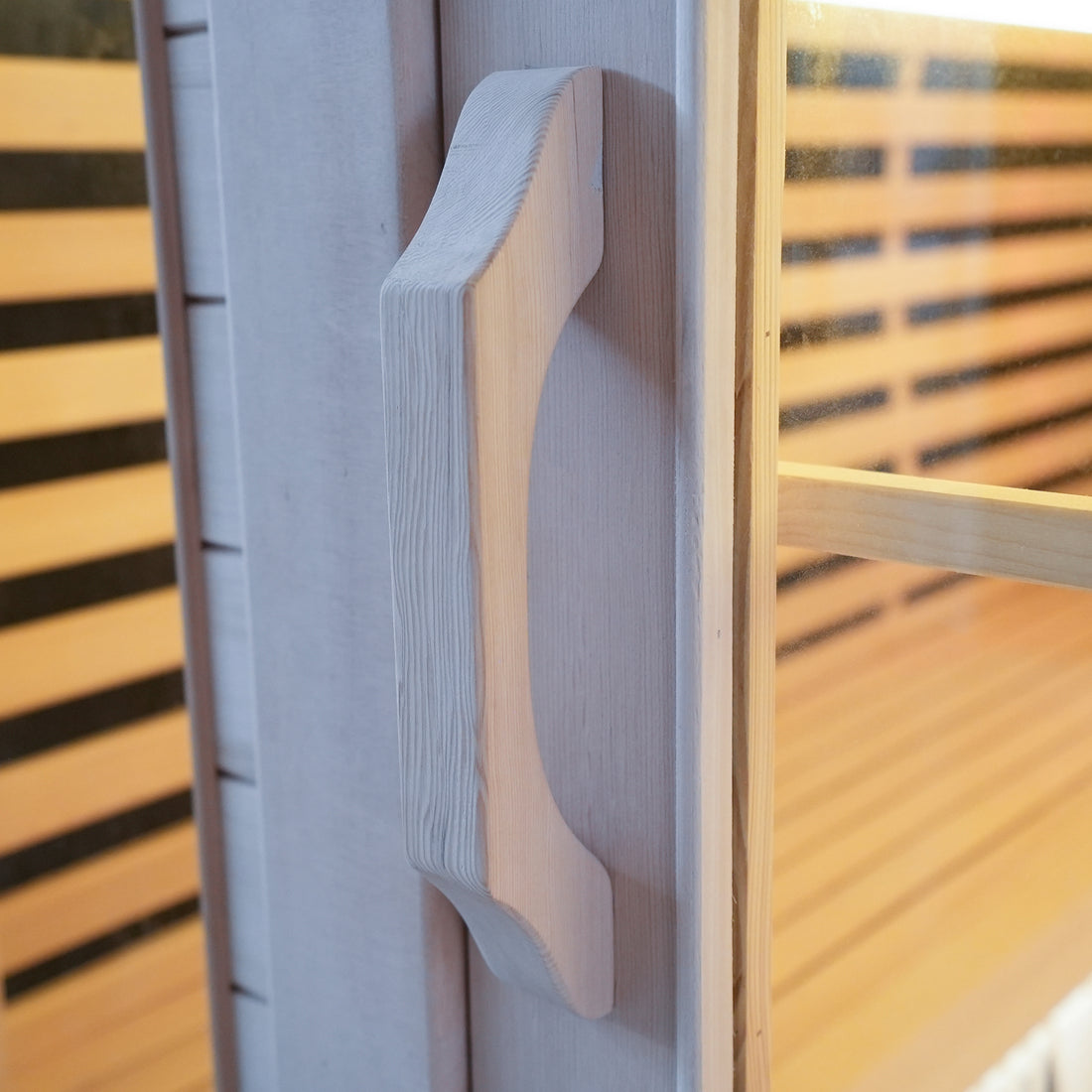 Close-up of a wooden sauna door handle on a glass door