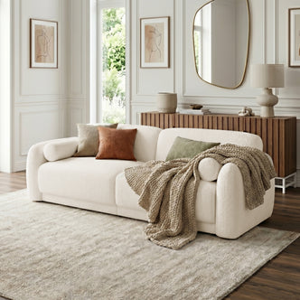 Cream-colored sofa styled in a living room with throw pillows and decorative elements