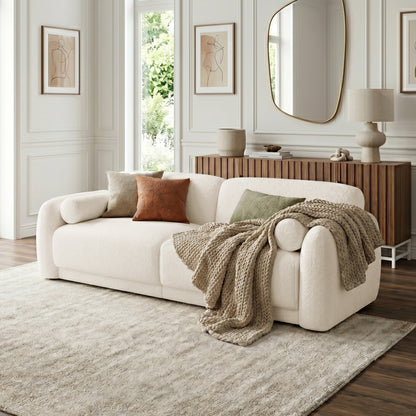 Cream-colored sofa styled in a living room with throw pillows and decorative elements