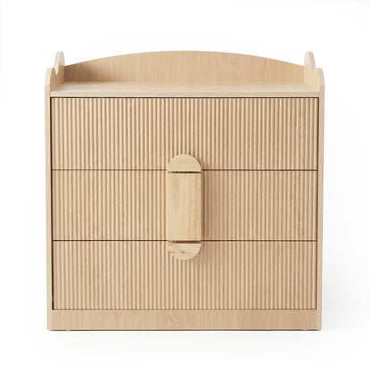 Light wood three-drawer dresser with fluted drawer fronts and raised edges on a white background