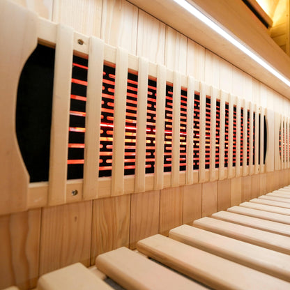 Side view of wooden sauna interior with bench and infrared heating panels
