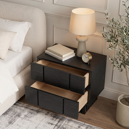 Black nightstand next to a bed in a styled bedroom