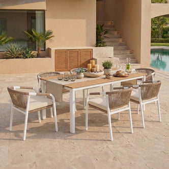 Vernon Outdoor Dining Chair Covers in Cream White protect woven rope-back chairs by a poolside table, enhancing style with easy-clean fabric for a refreshed look in modern outdoor settings.