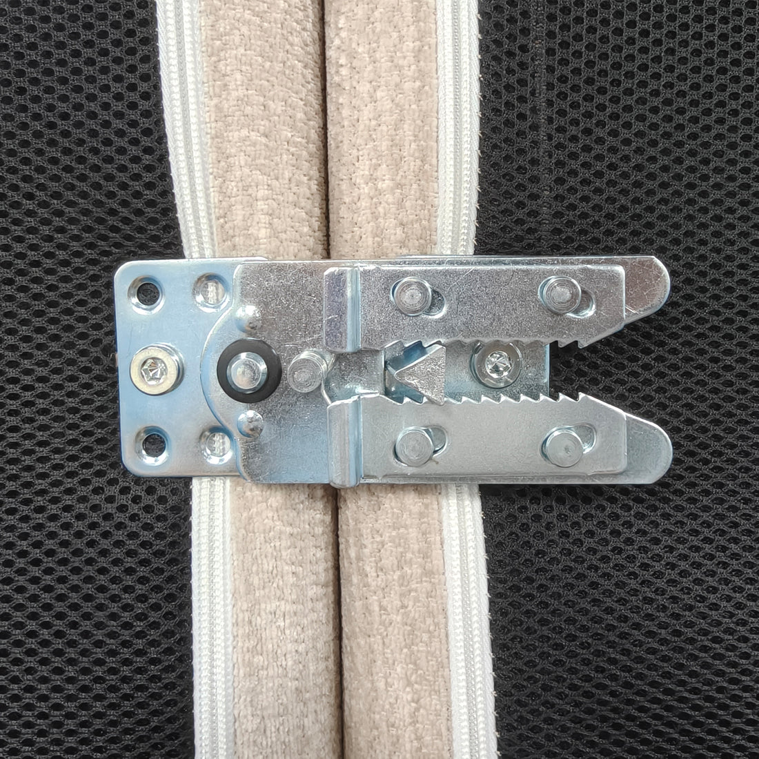 Close-up of a metal hinge mechanism attached to upholstered material
