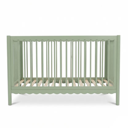 Sage green baby crib on white background highlighting scalloped bottom detail