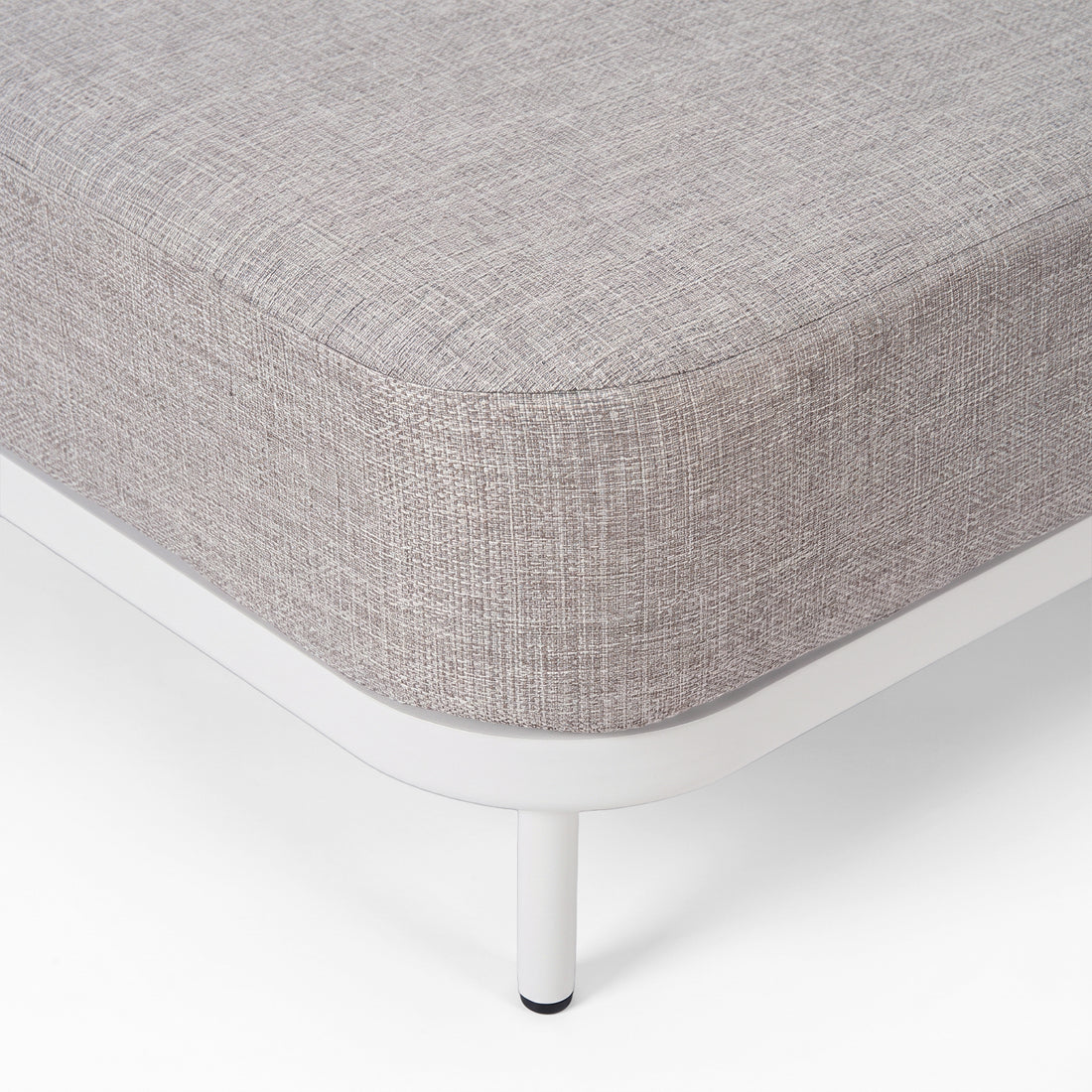 Close-up of the corner and leg of a modern upholstered furniture piece on a white background.