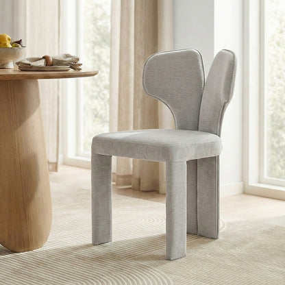 Two light gray upholstered chairs by a wooden dining table in bright room
